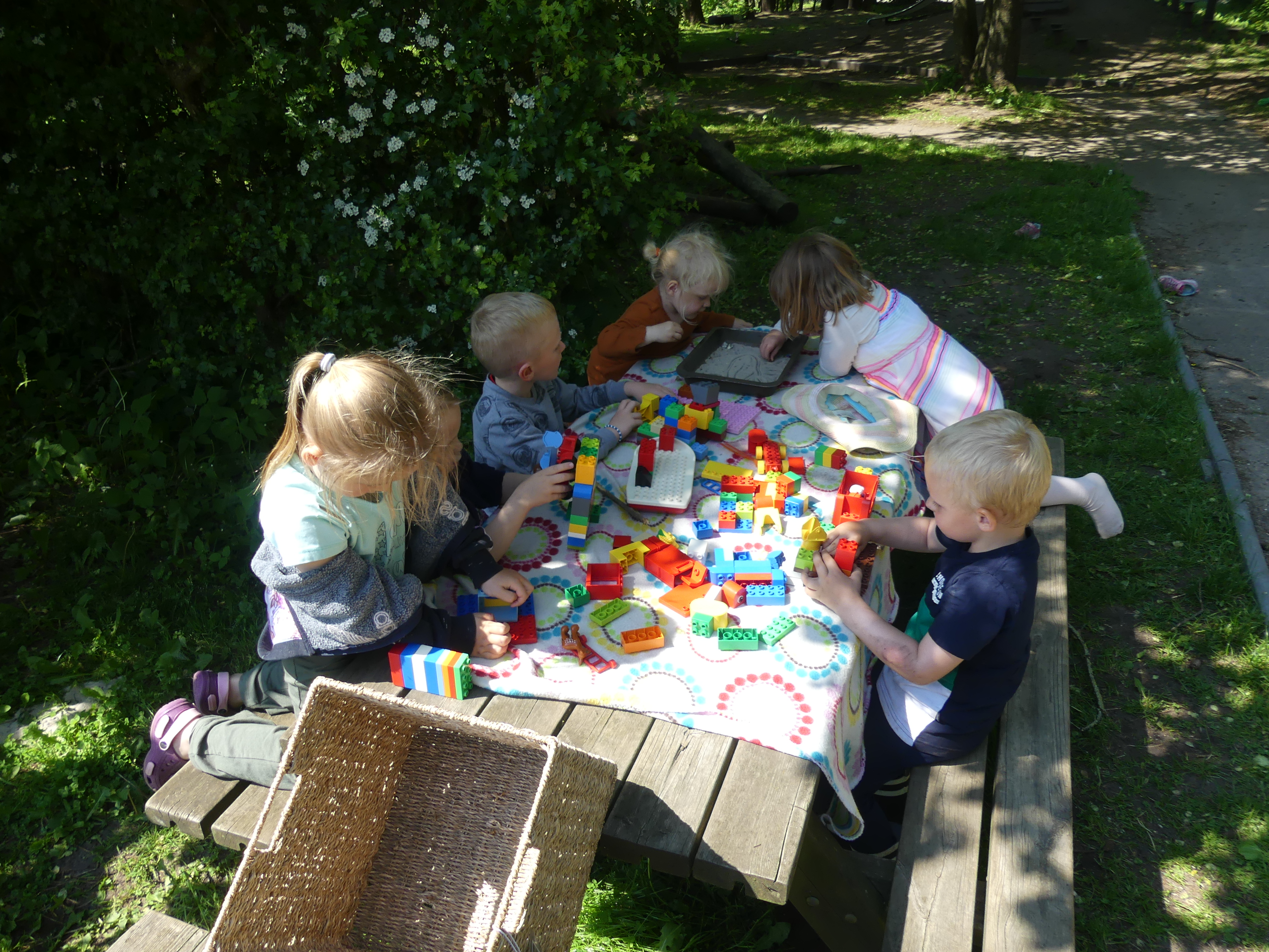 Børn bygger Duplo ved bord udenfor